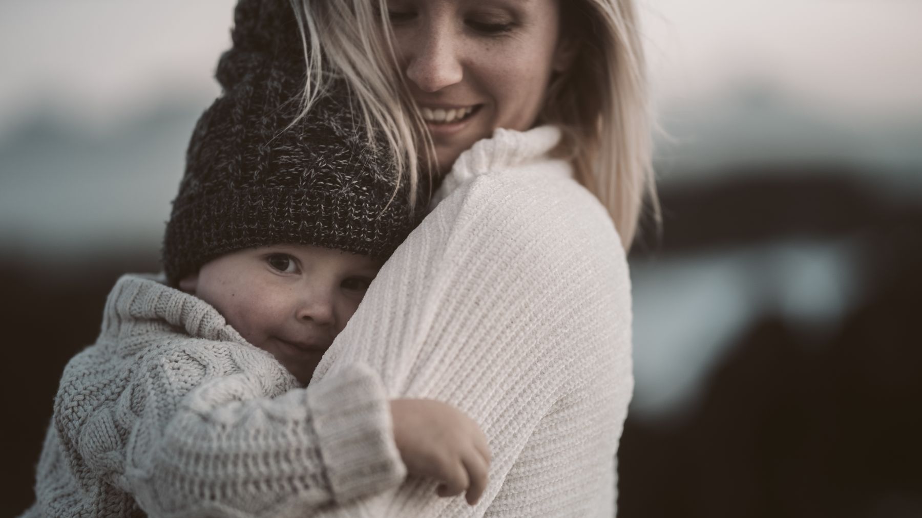 A smiling mother hugging her toddler